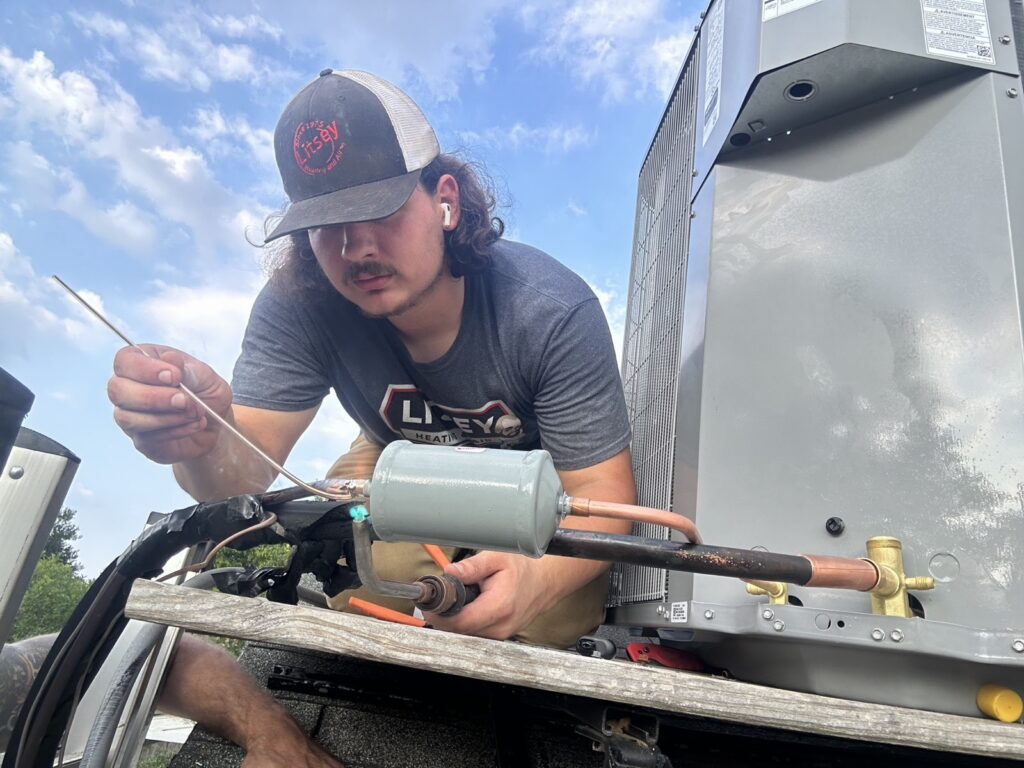 Litsey Heating and Air technician brazing copper refrigerant lines on a rooftop air conditioning unit in Louisville, KY